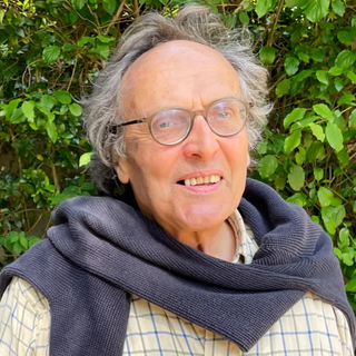 Nicolas Joly of Famille Joly, wearing glasses and a light-colored button-down shirt, stands with his arms crossed, looking off into the distance.