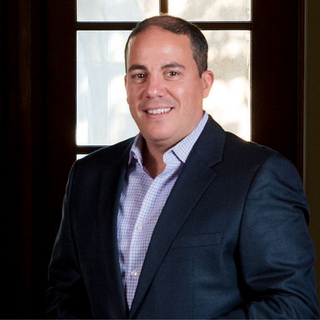 Headshot of WD President Rocco Lombardo in a dark suit, smiling in front of a window.
