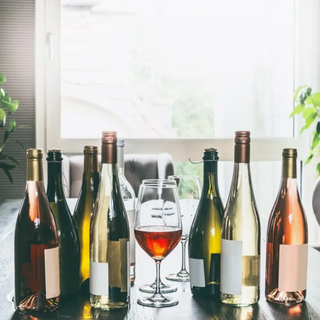 Unlabeled wine bottles arranged around three wine glasses on a gray tabletop.