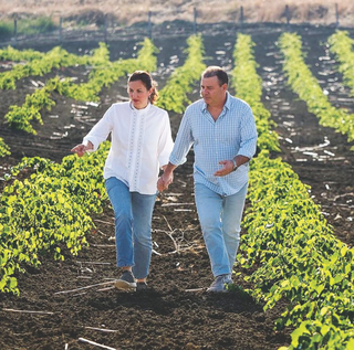 Fabio Sireci and Melissa Muller of Feudo Montoni walking together along vineyard rows.