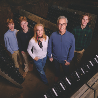The Davies family standing in a V-formation, with Proprietor Hugh Davies at the center, looking up at the camera and posing together.