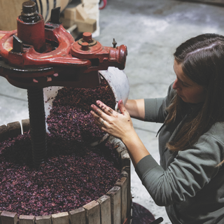 Juliette Alips of Domaine Les Monts Fournois standing at the grape press.