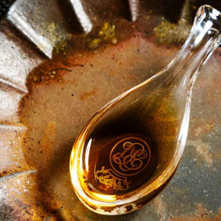 Golden liquid Royal Tokaji Essencia poured into a spoon, highlighting its rich amber color and syrup-like texture.