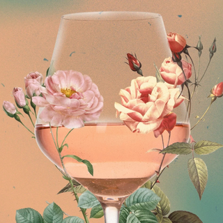 A glass of rosé wine with pink roses and leafy stems arranged around the glass, set against a soft gradient background.