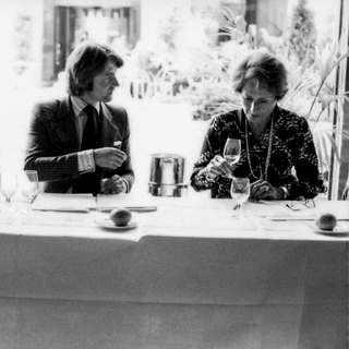 Black-and-white photo of two people seated at a table with a white tablecloth, evaluating wine during the 1976 Judgment of Paris tasting.