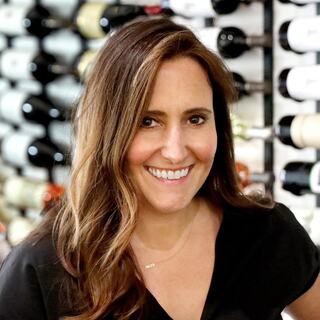 Wilson Daniels Executive Vice President of Sales and Marketing Shannon Coursey headshot. She is wearing a black top and smiling in the Wilson Daniels wine cellar.