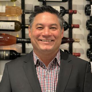 Vice President - Western Division Andy Lum poses in the Wilson Daniels wine cellar wearing a plaid shirt.