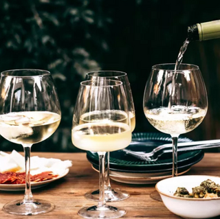 A photo of someone pouring white wine into a wine glass.