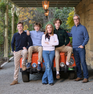 A photo of the Davies family featuring Davies Vineyard Proprietor Hugh Davies, his wife, and their three sons. The family is posed on and in front of a vibrant orange car.